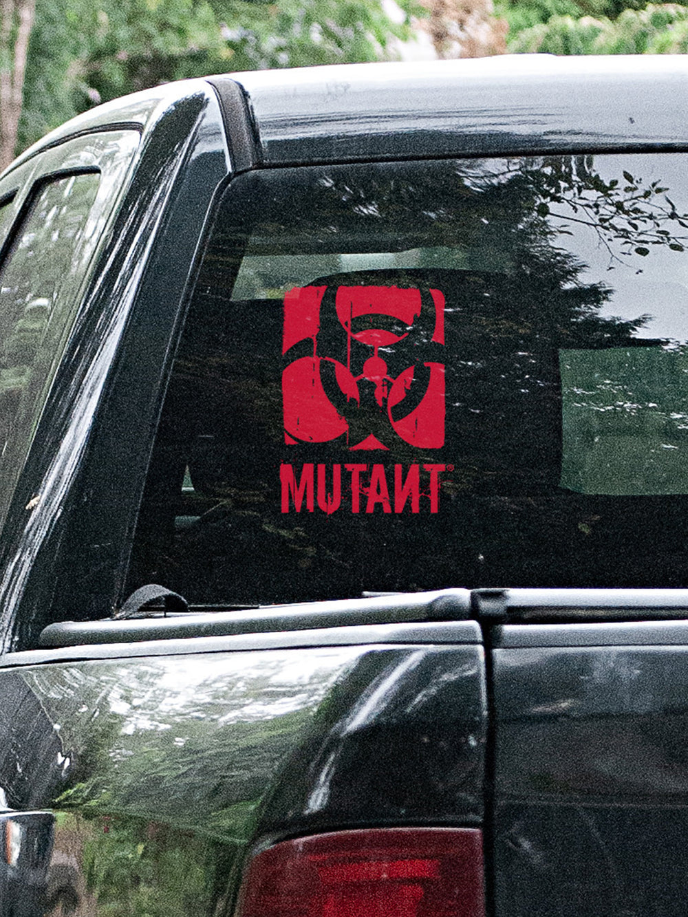 A photo showing the Rugged Truck Window Decal, which features the MUTANT logo in red, applied to the rear glass of a truck.