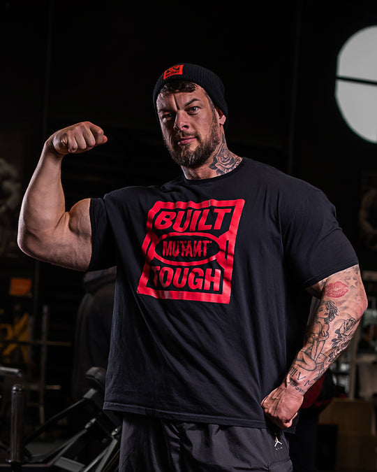 Jamie Christian, The Mutant Giant, at the gym wearing the black 'MUTANT's Truck Month' t-shirt, which features the 'Built Mutant Tough' phrase in red letters.