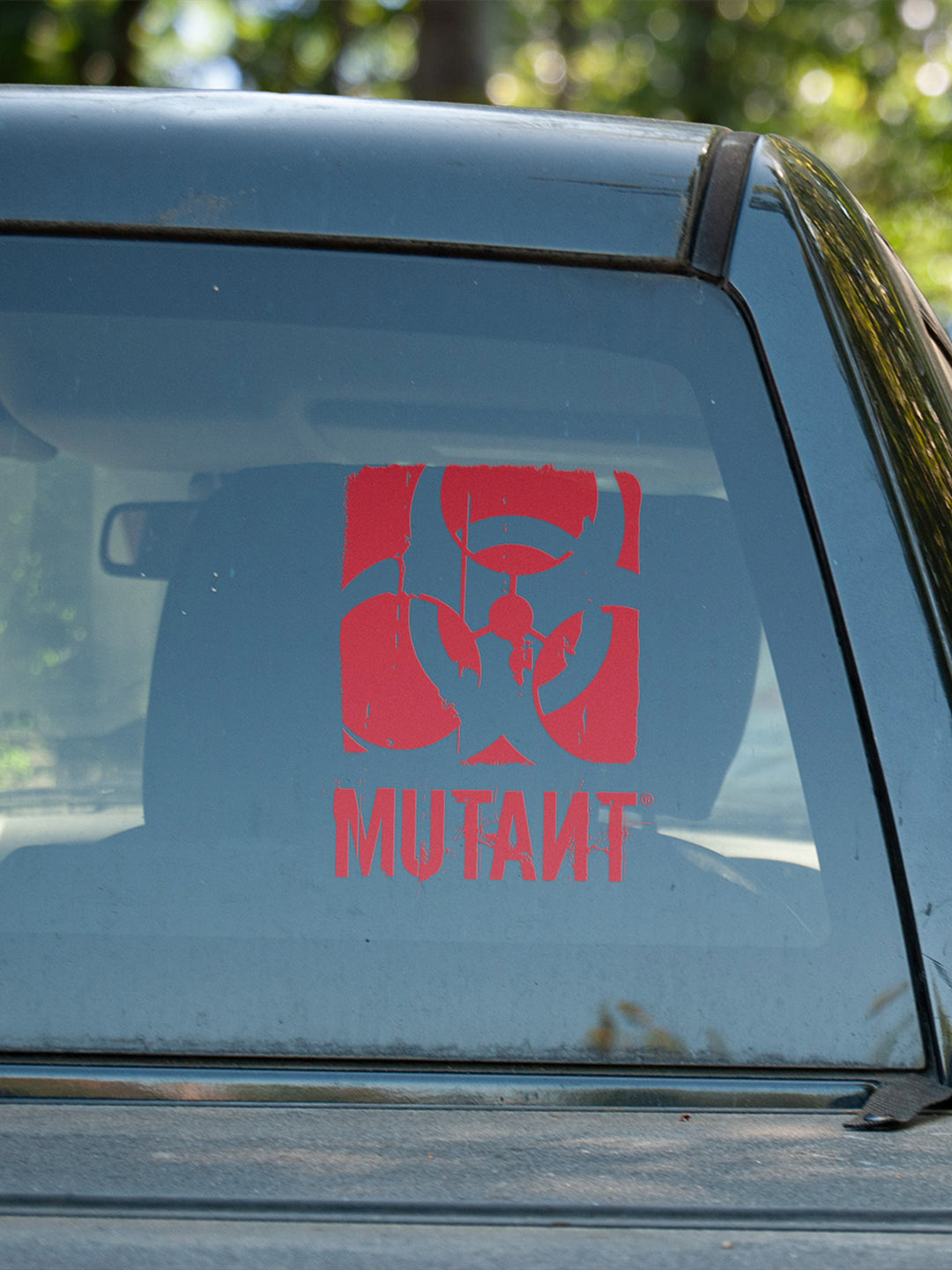 A photo showing the Rugged Truck Window Decal, which features the MUTANT logo in red, applied to the rear glass of a truck.