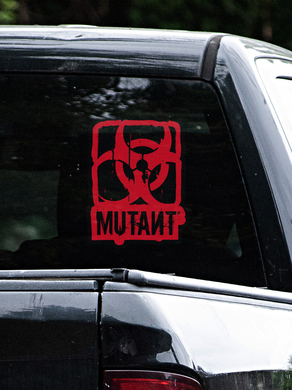 A photo showing the Rugged Truck Window Decal, which features the MUTANT logo in red on a shaped black background, applied to the rear glass of a truck.