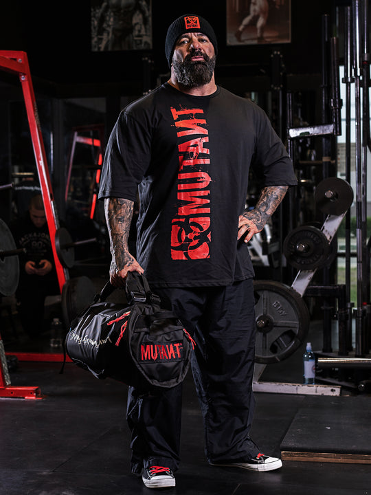 Dusty Hanshaw at the gym, holding the black Military Top Load Duffel Backpack by its straps